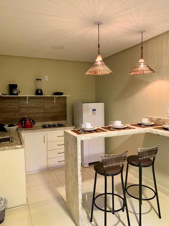 a kitchen with two bar stools and a counter at Casinhas da Vila - Itacaré in Itacaré
