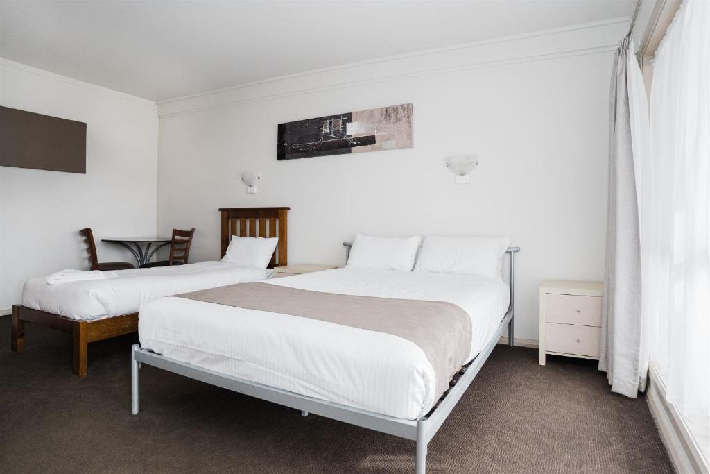 two beds in a bedroom with white walls at Hurley's Bar & Bistro in Kyabram