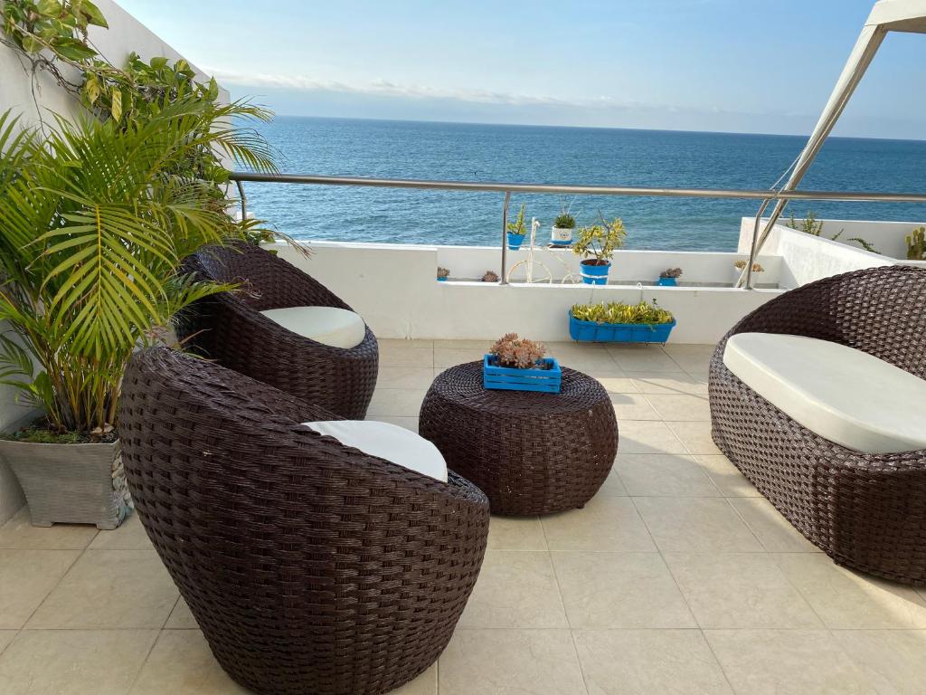balcón con sillas de mimbre y vistas al océano en Departamentos Amoblados Frente al Mar Manta -PROINKASA en Manta