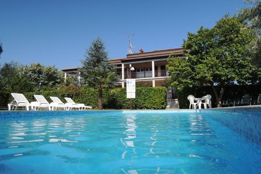 une piscine avec des chaises blanches et une maison dans l'établissement Bungalow Porec (4400-1), à Poreč