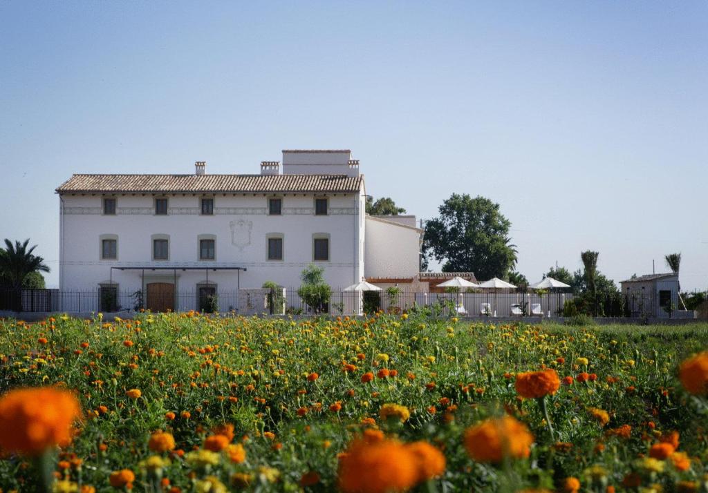 um campo de flores em frente a um edifício branco em La Mozaira em Alboraya