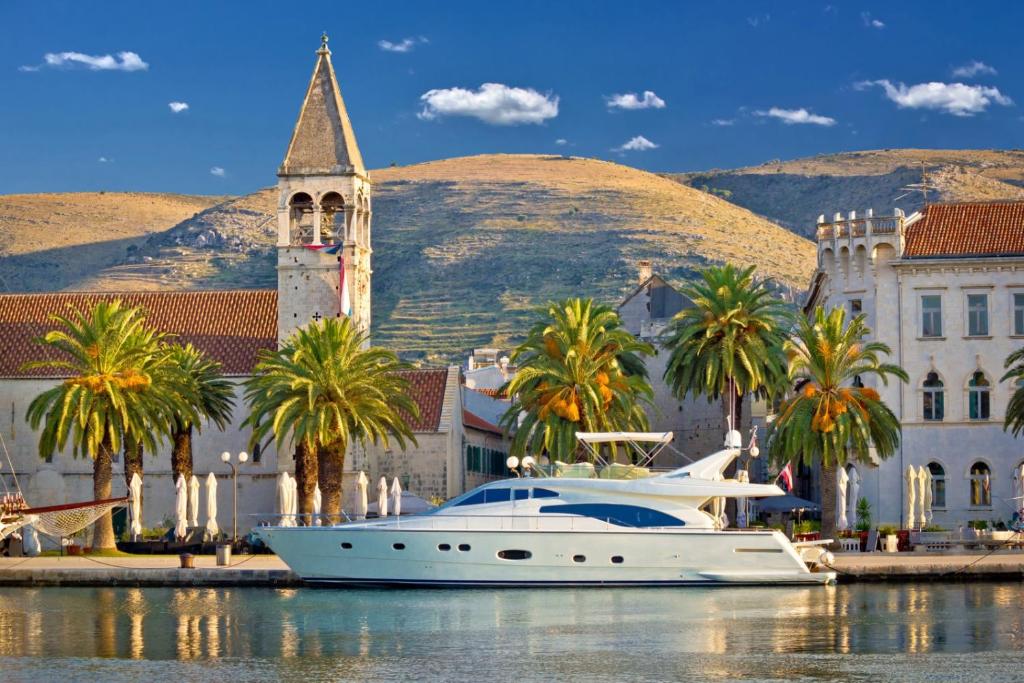 a white boat in the water in front of a building at Apartment in Trogir with sea view, terrace, air conditioning, Wi-Fi (3788-2) in Trogir