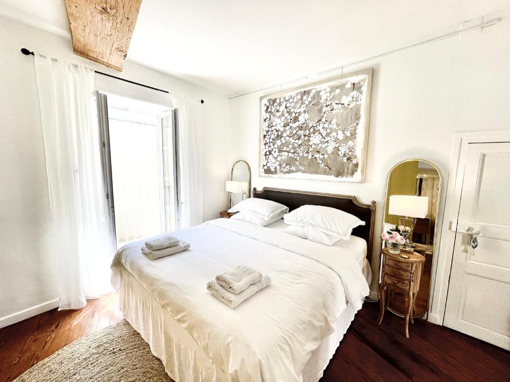 a white bedroom with a large bed with two towels on it at Grand Cru, Appartement au Centre Médiéval de Beaune in Beaune