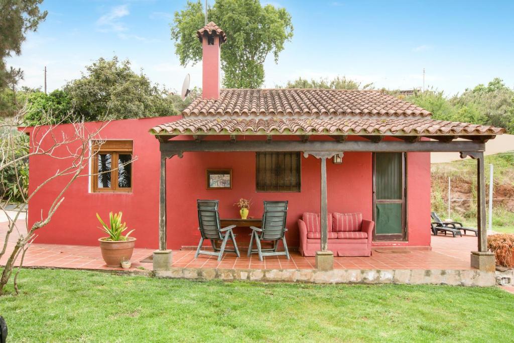 a red house with a table and chairs on a deck at La Finca de Teror in Teror