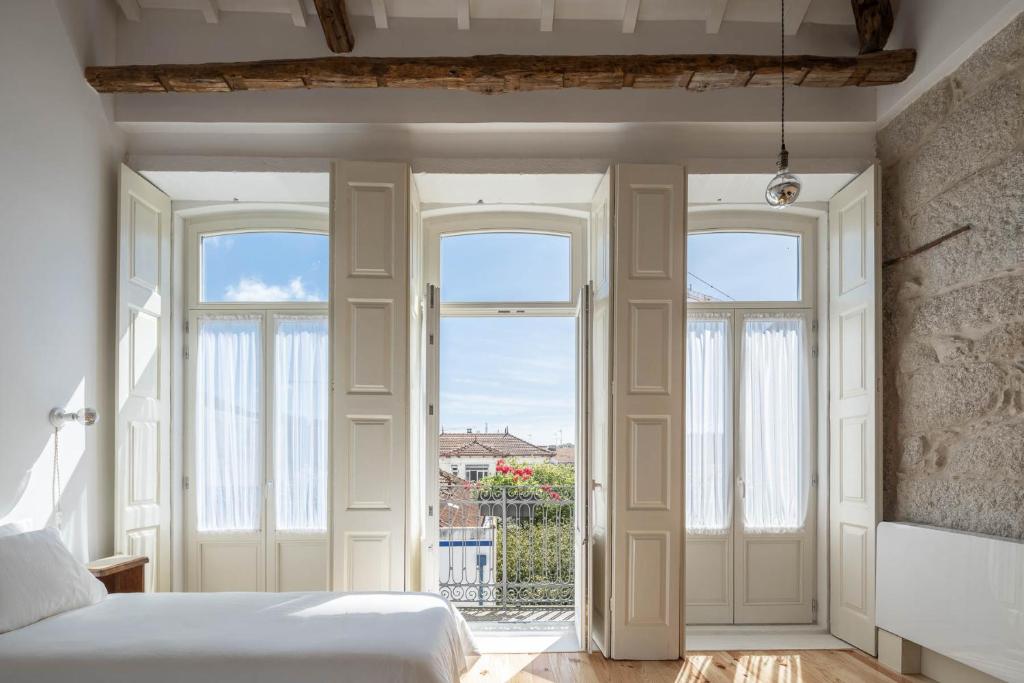 a bedroom with a bed and two windows at Uba - Heritage and Wine in Porto