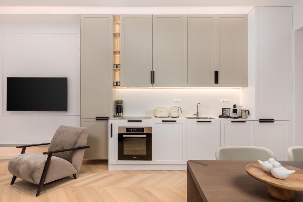 a kitchen with white cabinets and a table and a chair at Plaza Apartments in Opatija