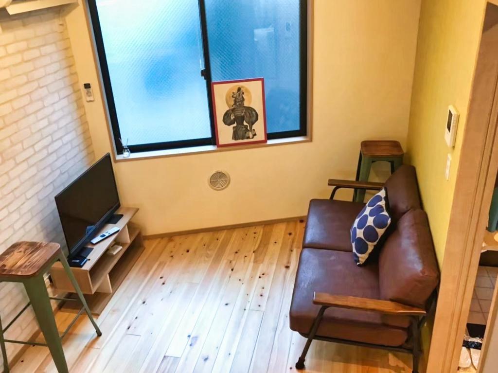a living room with a leather couch and a tv at JR Tokyo family room @Otsuka Bovine 101 in Tokyo