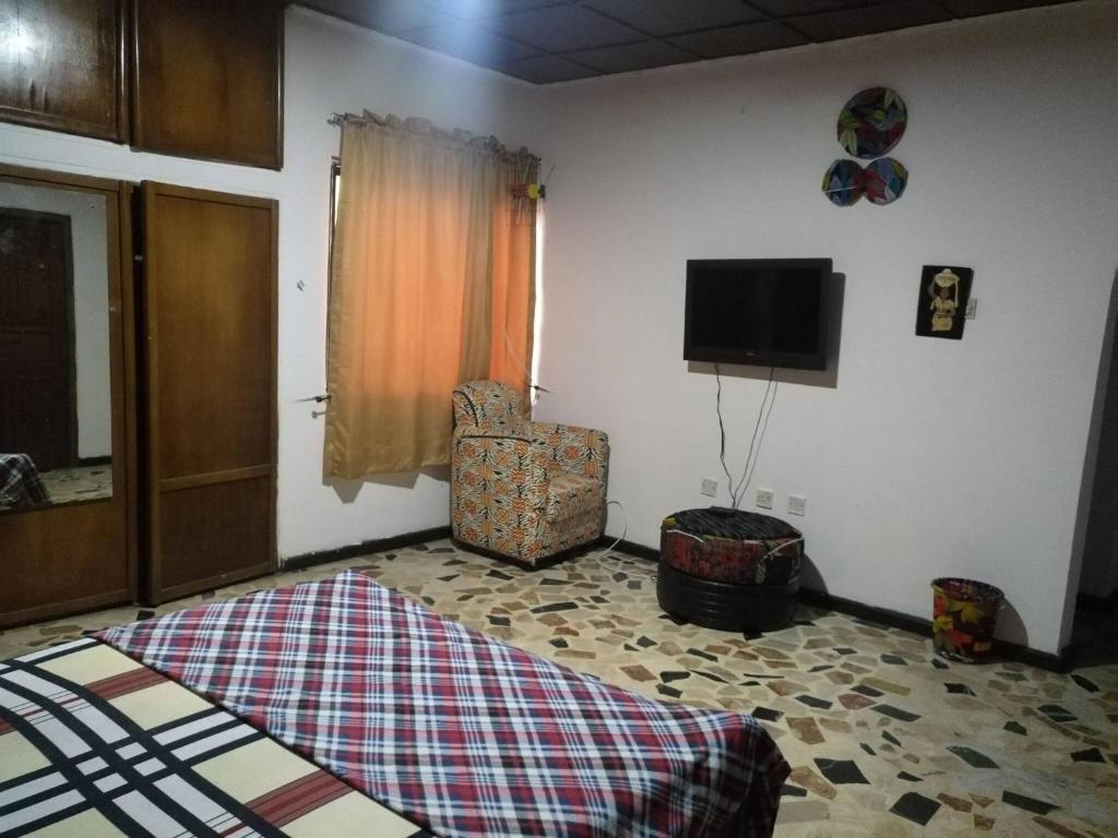 a bedroom with a bed and a chair and a television at Room in House - The Village Apartments, Gbagada O9o98o58ooo in Lagos