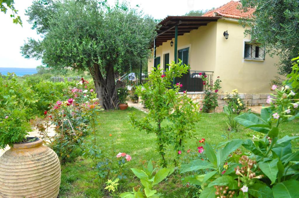 una casa con un jardín con flores en el patio en Holiday House Angelos A on Agios Gordios Beach en Agios Gordios