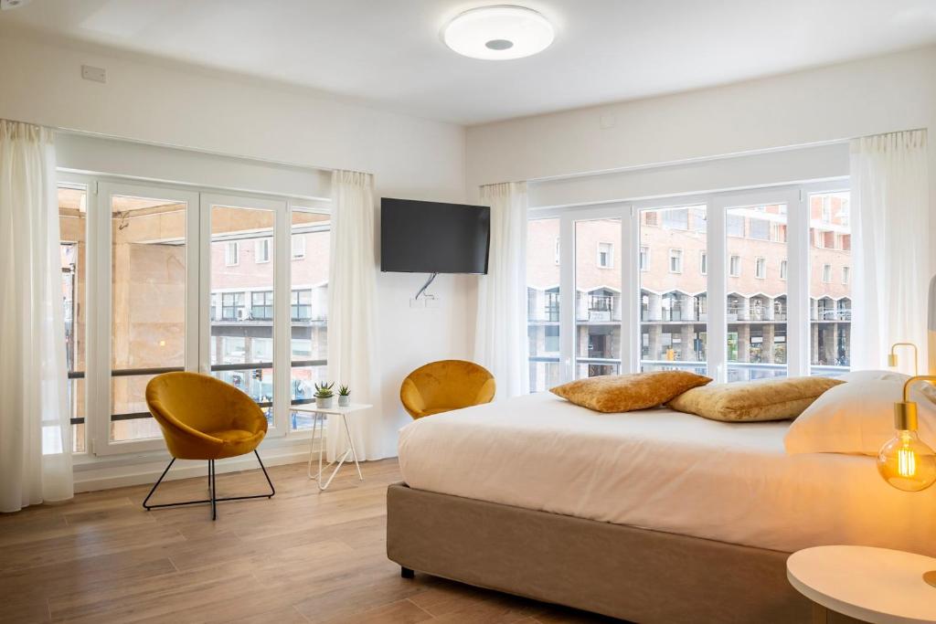 ein weißes Schlafzimmer mit einem großen Bett und Fenstern in der Unterkunft Marconi28suites in Bologna