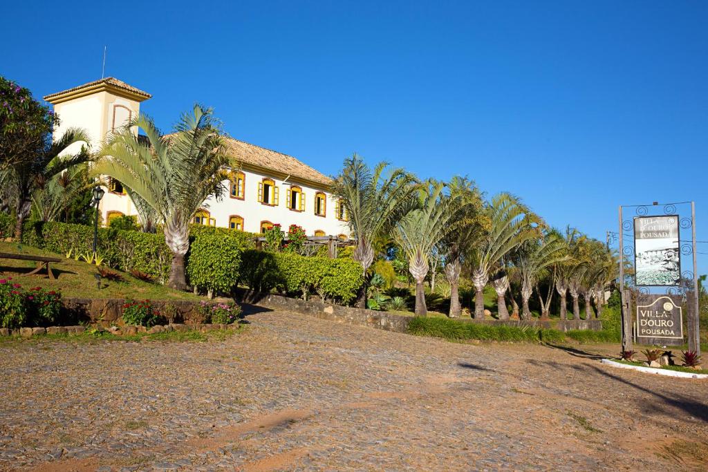 un edificio con palmeras frente a una carretera en Villa D'Ouro Pousada, en Tiradentes