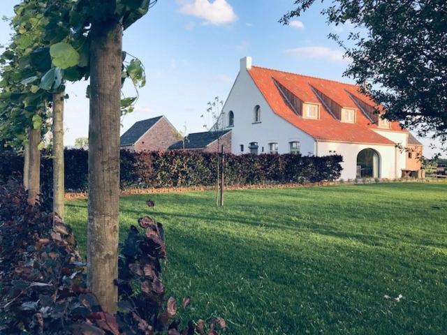 une grande maison blanche avec un toit orange dans l'établissement B&B Biesvenhof, à Merksplas