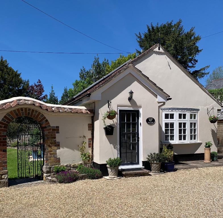 een wit huis met een poort op een oprit bij Tolpuddle Hideaway, Tolpuddle, Dorset in Dorchester