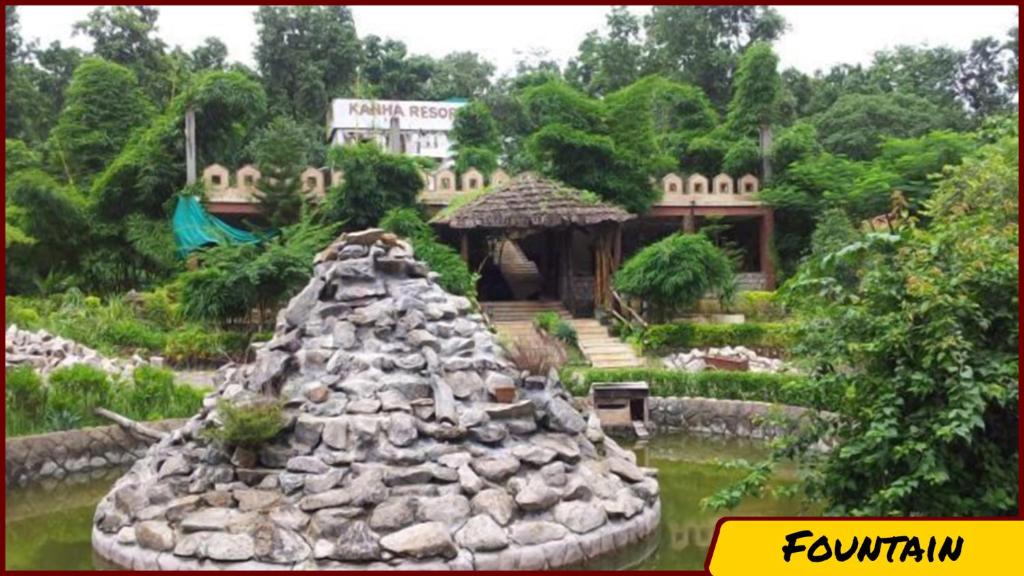 un jardín con una estructura rocosa en el agua en Kanha Resort, en Kānha