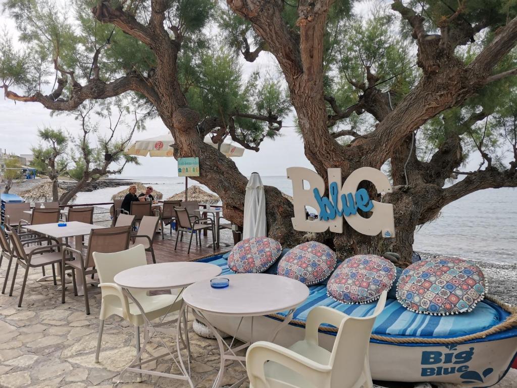 een tafel en stoelen op het strand naast een boom bij Βig Βlue Apartments in Makry Gialos