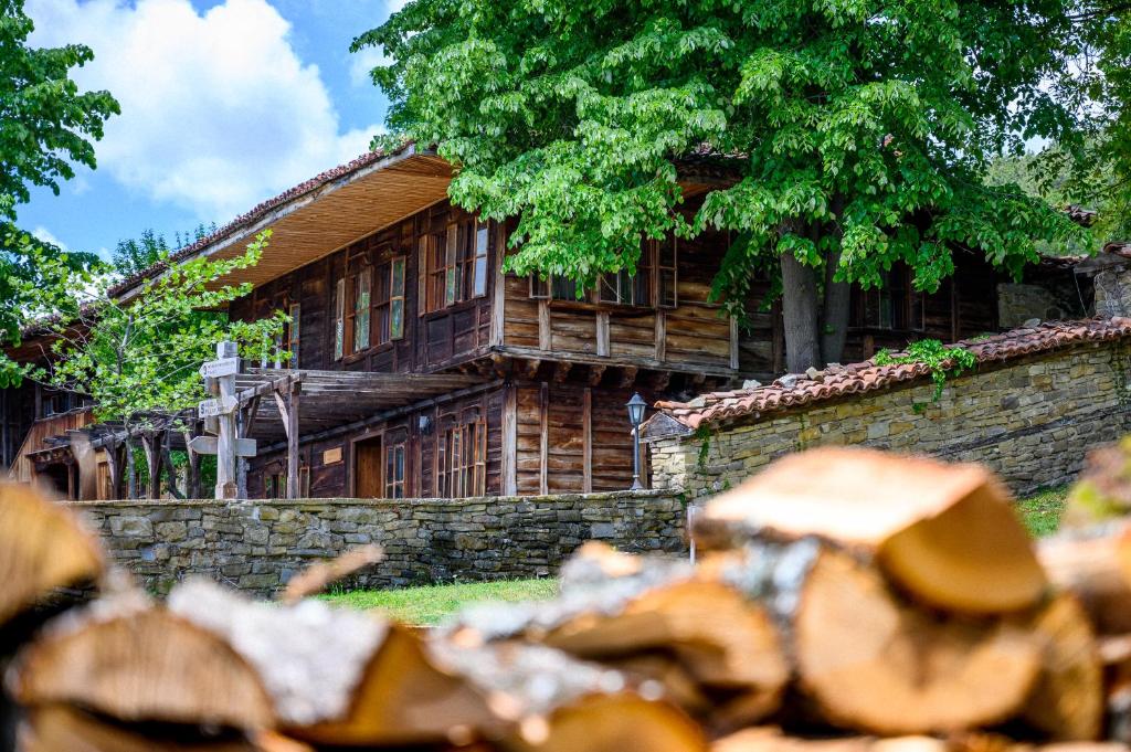 a large wooden house with a stone wall at Guest Houses "Zlatna Oresha - Complex" in Zheravna