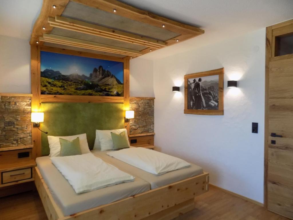 1 dormitorio con 1 cama y una pintura en la pared en Appartements Obergollerhof, en Assling