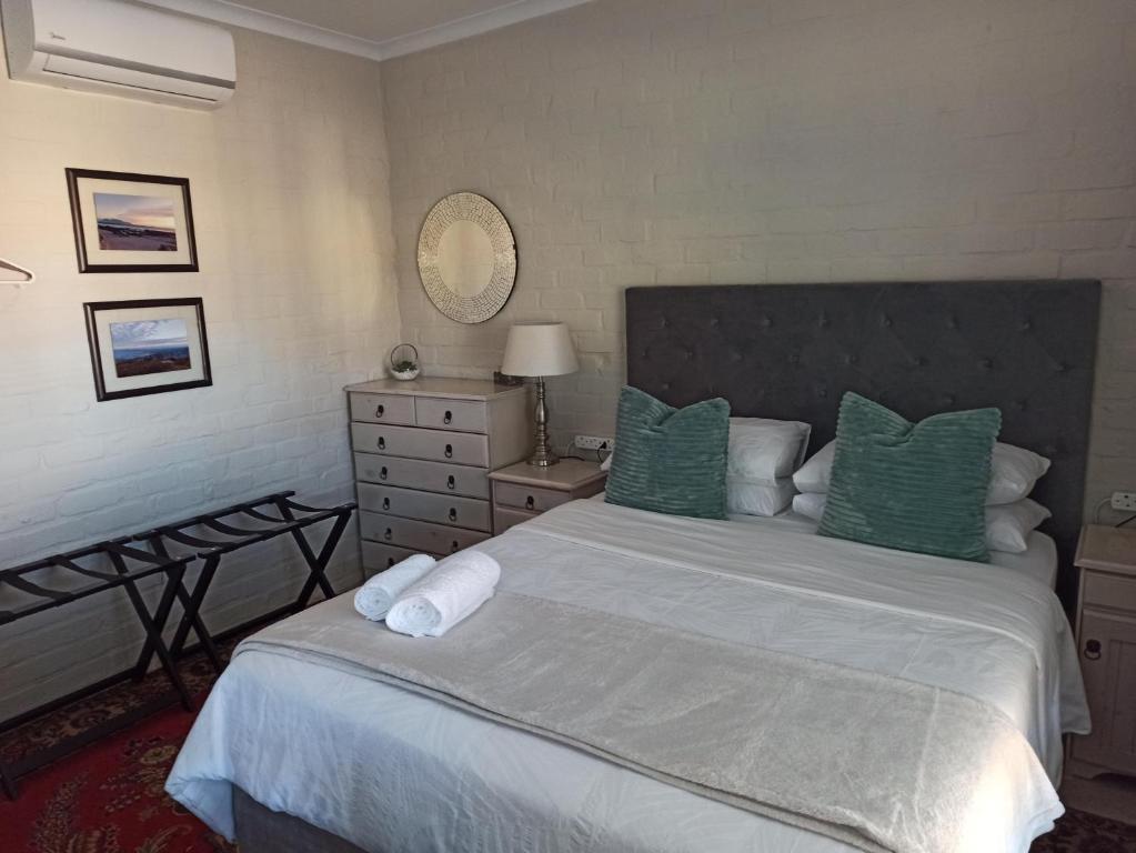 a bedroom with a large bed with green pillows at 17Peppertree in Cape Town