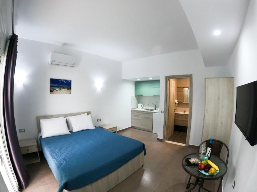 a small bedroom with a blue bed and a kitchen at Red Hibiscus Stegna in Archangelos