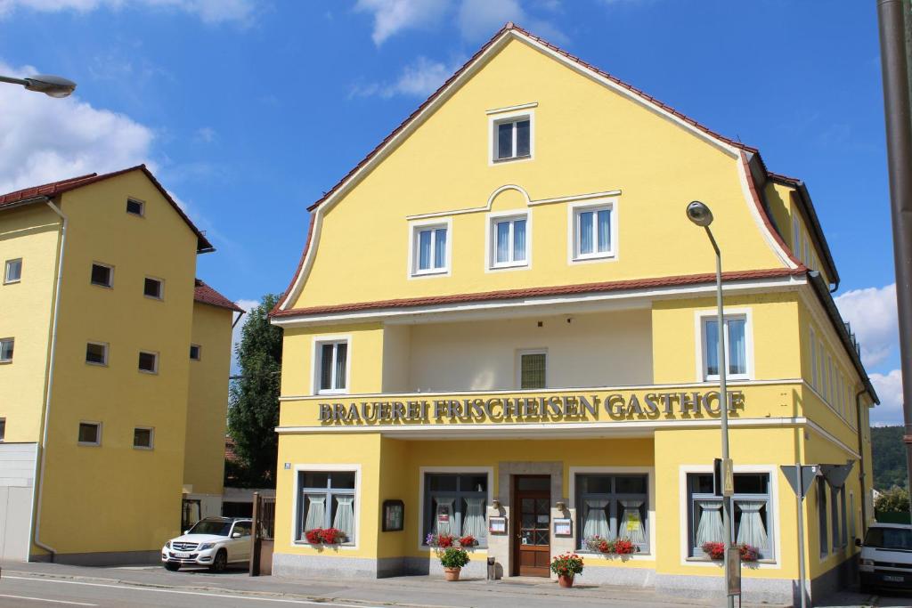 een geel gebouw met een bord ervoor bij Brauerei und Gasthof Frischeisen in Kelheim