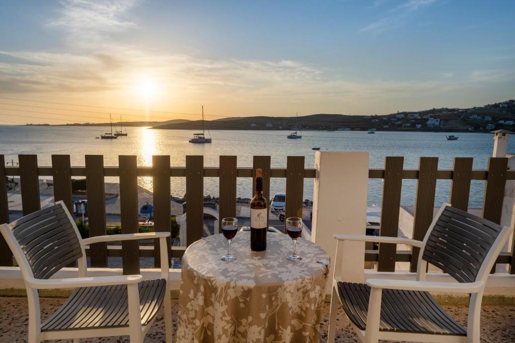 a table with two glasses of wine on a balcony with the ocean at Stella Hotel in Parikia