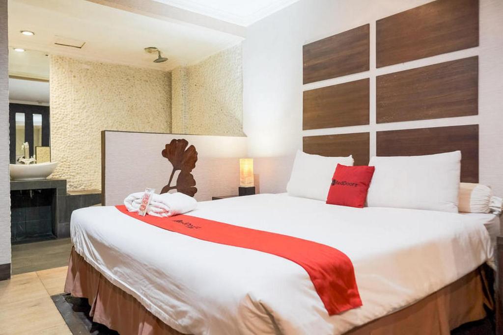 1 dormitorio con 1 cama blanca grande con almohadas rojas en RedDoorz near Waterboom Lippo Cikarang, en Cikarang