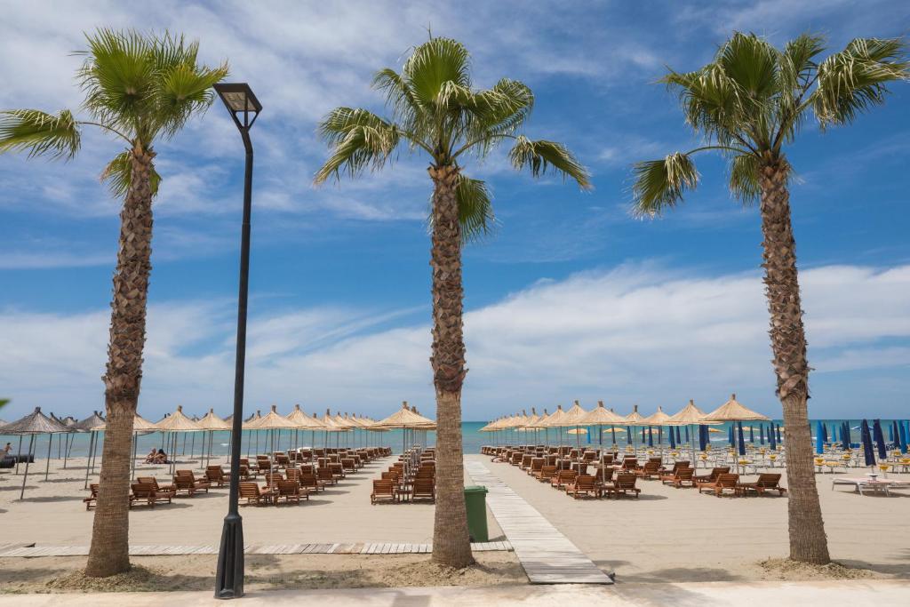 una playa con sillas, palmeras y sombrillas en Mirage Hotel, en Golem