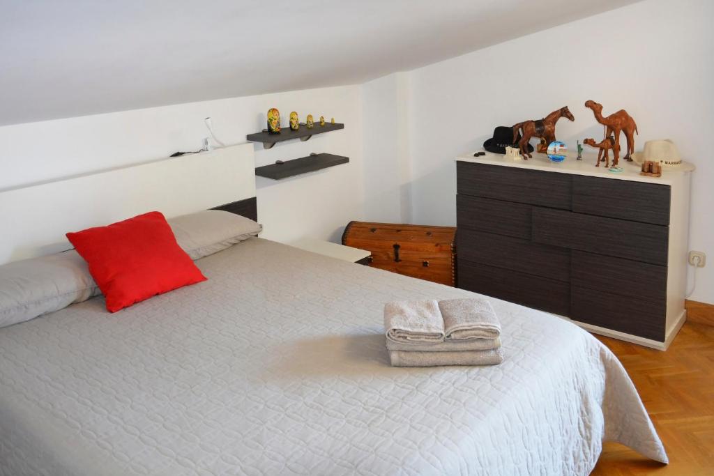 um quarto com uma cama com uma almofada vermelha e uma cómoda em Apartamento en Villa con parking em Añorga-Lugariz