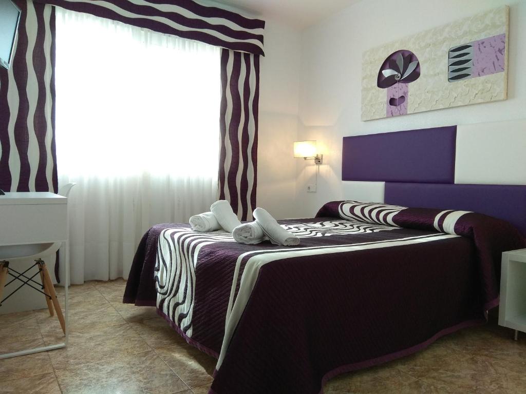 1 dormitorio con 1 cama con sábanas moradas y blancas en Hotel Restaurante Campomar en Cartagena