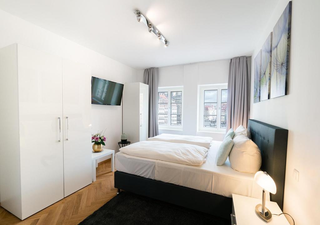 ein weißes Schlafzimmer mit einem Bett und einem Fenster in der Unterkunft Familienapartment An der Frauenkirche in Dresden