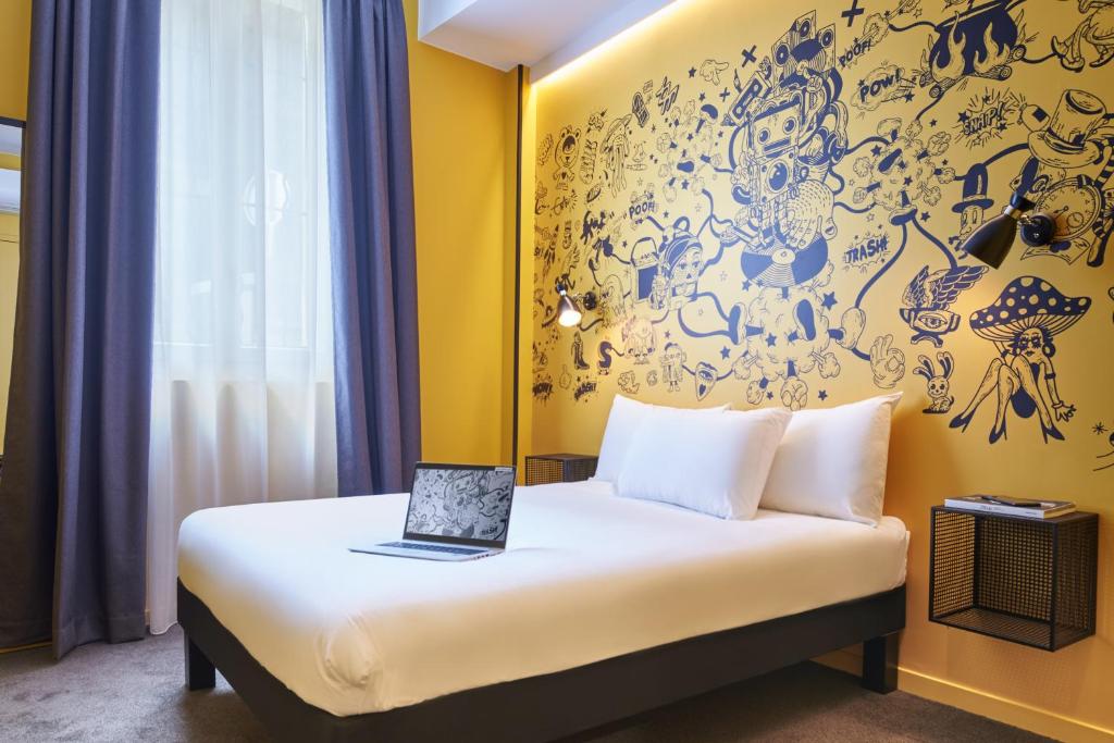 a bedroom with a bed with a laptop on it at Ibis Styles Paris Gare de l'Est Magenta in Paris