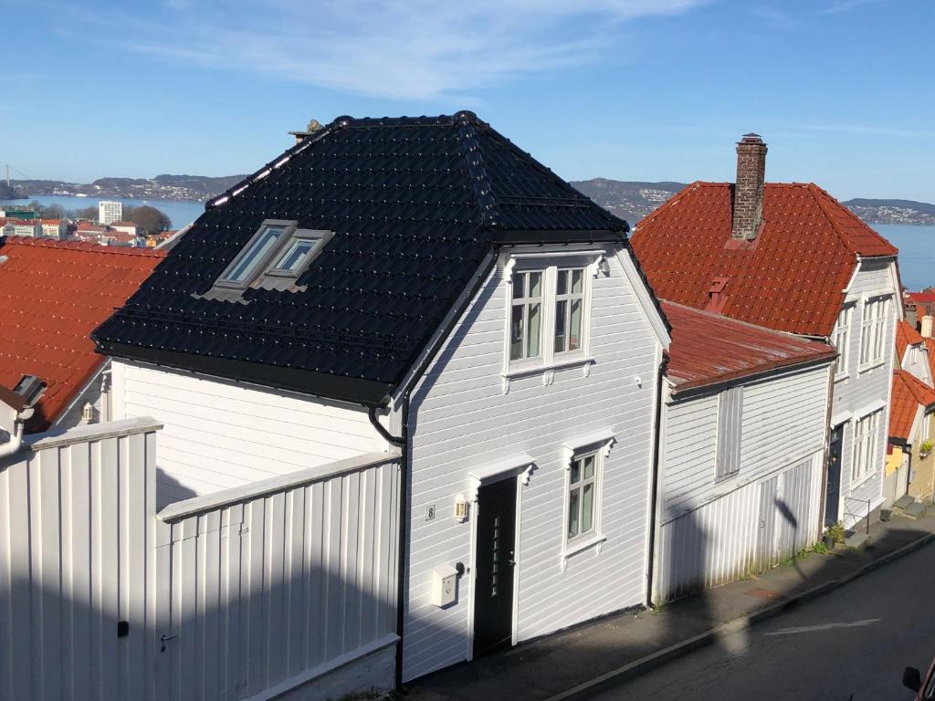 ein weißes Haus mit schwarzem Dach und roten Dächern in der Unterkunft Villa Skansen in Bergen