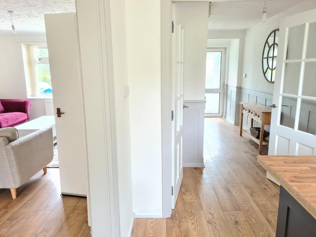 uma cozinha e sala de estar com paredes brancas e pisos de madeira em Beach Chalet, Little Walsingham Norfolk em Little Walsingham