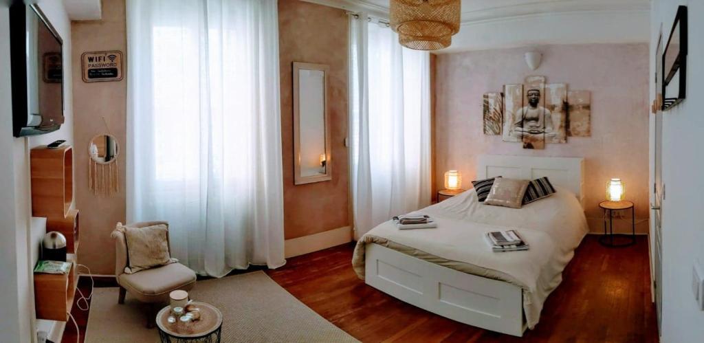 a bedroom with a white bed and a chair at Couette et Tartine in Chalon-sur-Saône