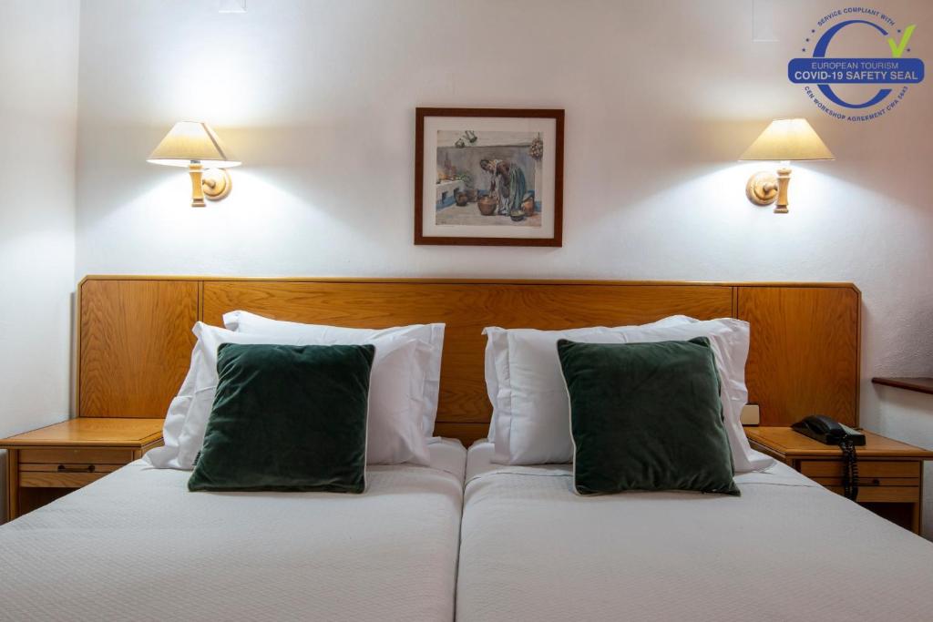 two beds with green pillows in a hotel room at Pantanha Apartment by Trip2Portugal in Nelas