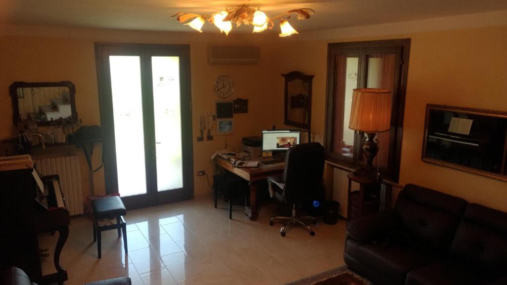 Ca' Le Rose في Bagnolo San Vito: غرفة معيشة مع مكتب عليه كمبيوتر