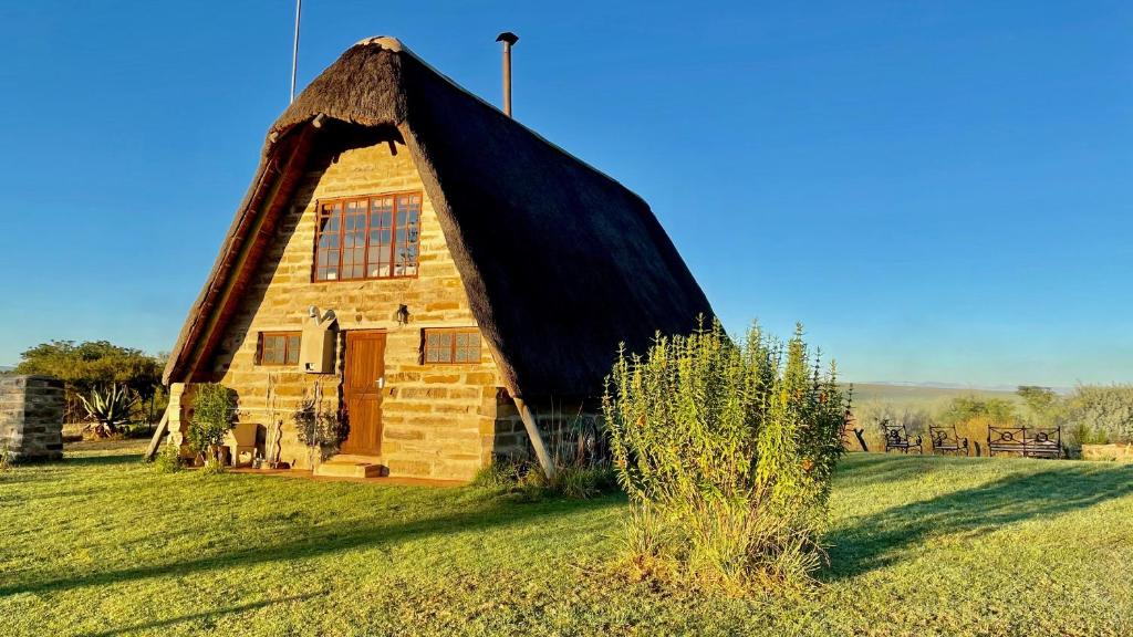 a house with a thatched roof on a field at Tugela River Lodge in Winterton