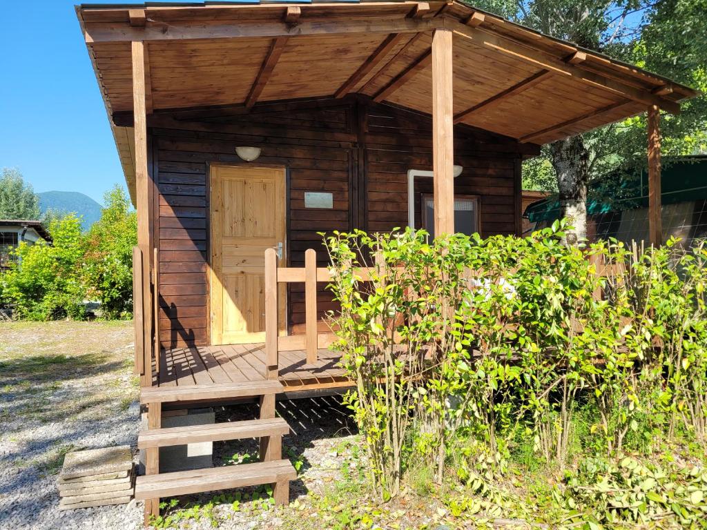 a small wooden cabin with a porch and a wooden door at Barumi-Bungalow Michelangelo in Porlezza