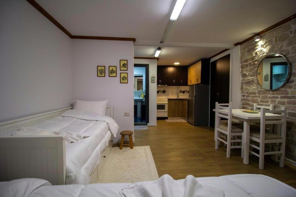 a room with two beds and a table and a kitchen at Solhouse in Gjirokastër