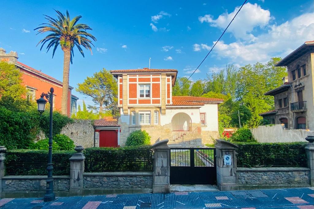 a house with a palm tree and a fence at Casa Vacacional Galiana in Avilés