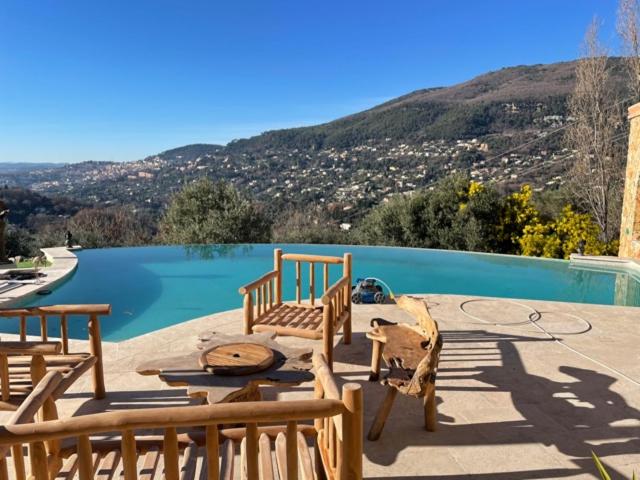 un patio con tavolo e sedie accanto alla piscina di Le Clos des Senteurs de Chateauneuf de Grasse a Châteauneuf