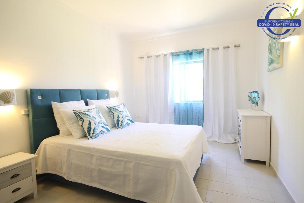 a bedroom with a bed with a blue headboard and a window at Quinta Nova Apartment by Trip2Portugal in Alvor