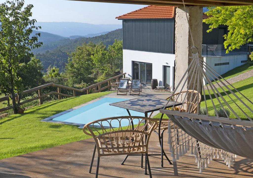 a patio with a hammock and a table and chairs at Cimo da Vinha - Nature Spot in Castelo de Paiva