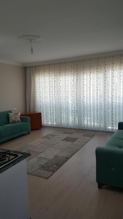 a living room with a green couch and curtains at 1+1 furnished flat with pool in Lara