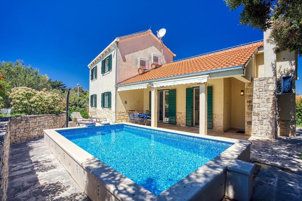 a swimming pool in front of a house at NEW! Villa SAN with heated pool, traditional surroundings, 3-bedrooms in Nerežišće
