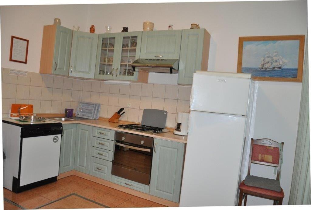 a kitchen with green cabinets and a white refrigerator at House Lopar (899) in Lopar
