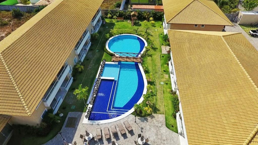 uma vista superior de uma piscina entre dois edifícios em Guarajuba Village Verano A01, térreo - GUARAJUBA TEMPORADA, viva mais de uma experiência de hospedagem conosco! em Guarajuba