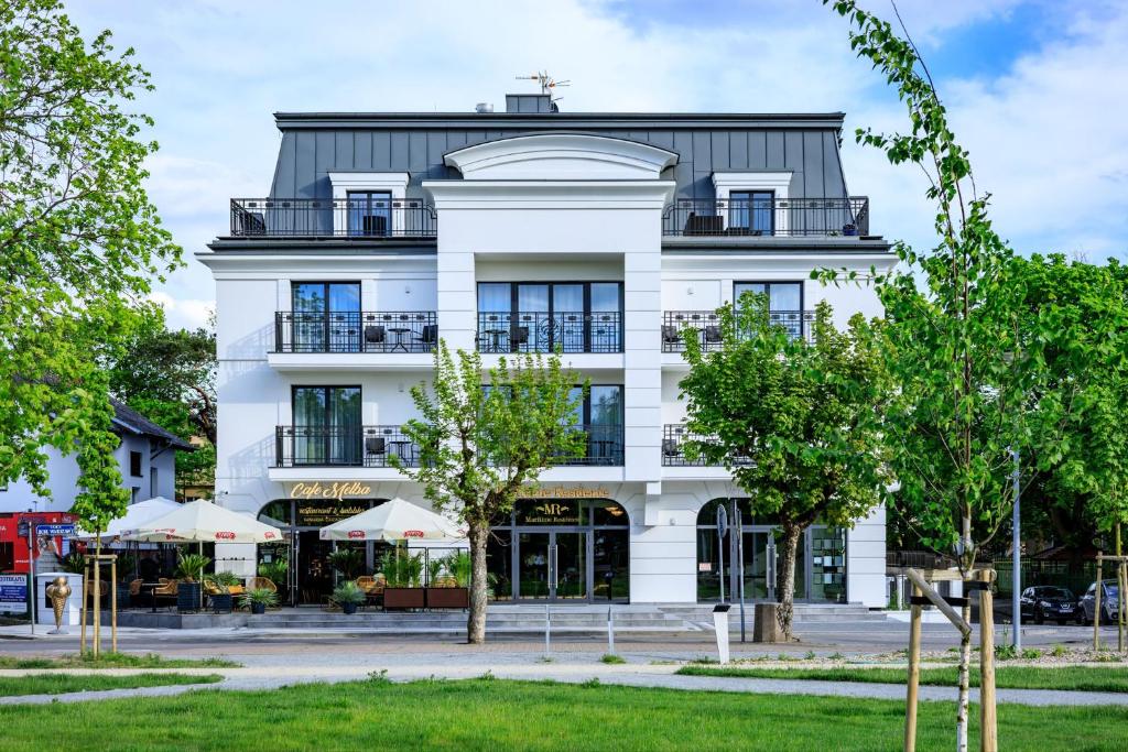 a white building with trees in front of it at Maritime Residence in Międzyzdroje