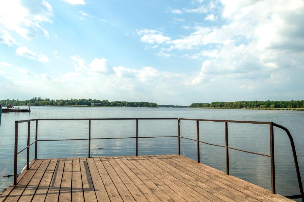 un muelle en un lago con un cielo nublado en Коттедж на базе отдыха у реки с. Кудашевка, en Kudashevka