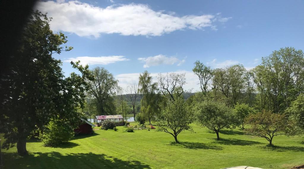 un champ avec des arbres et une maison au loin dans l'établissement Kastellegården, à Kungälv